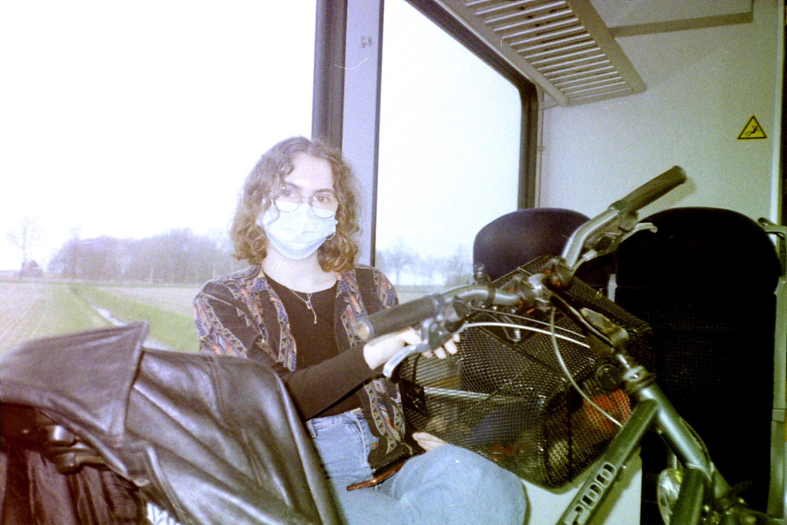 dani on a train with a mask on and a bike
